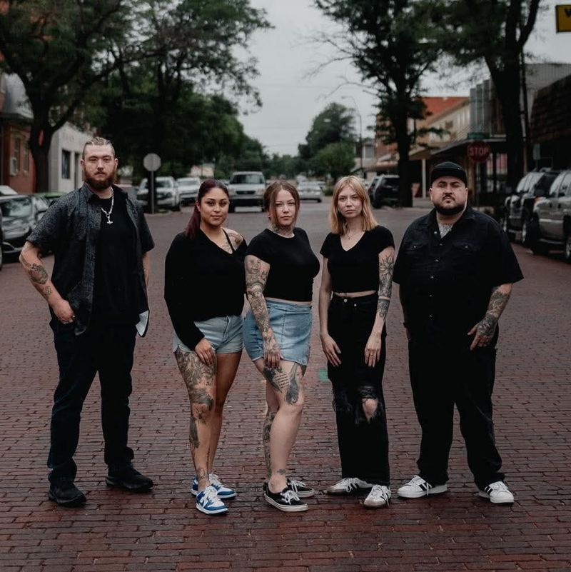 The five EZ Ink Studios artists standing together on a brick street
